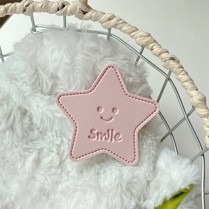 Macro shot of pink leather star-shaped phone grip with smile logo and stitch detail