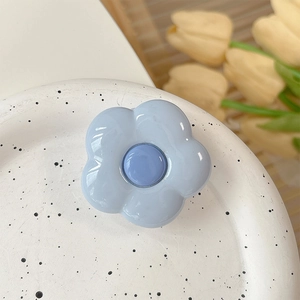 Detailed close-up of light blue flower phone grip with glossy resin finish on ceramic plate