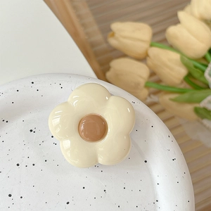 Detail of cream white flower phone grip stand with coffee brown center on artistic plate