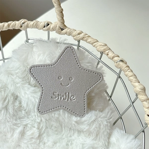 Detail of gray star-shaped leather phone socket with smile engraving and stitching