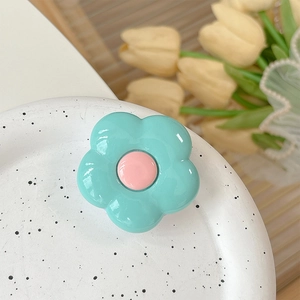 Detail of mint green flower phone grip holder with pink center on a ceramic plate