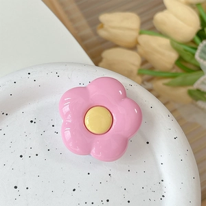 Detailed view of a pink flower phone griptok placed on a white ceramic plate