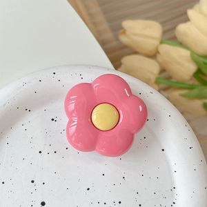 Close-up of a pink flower phone grip holder on a decorative ceramic tray