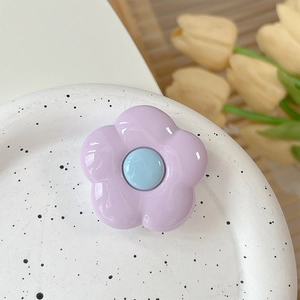 Close-up of a floral phone grip with purple petals on a decorative ceramic tray