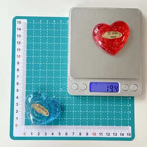 Vista macro del supporto a cuore trasparente con glitter e logo dorato sulla bilancia