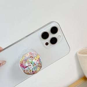 Detail of round transparent phone grip with colorful sequins and collapsible base