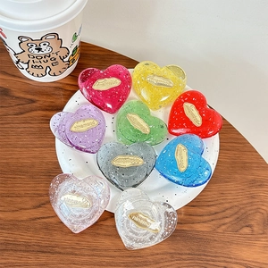 Supporti per telefono a forma di cuore con glitter in vari colori su un piatto elegante