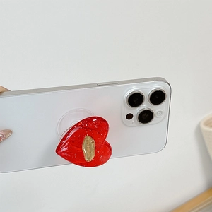 Dettaglio del supporto per telefono a cuore rosso glitterato con emblema dorato su smartphone
