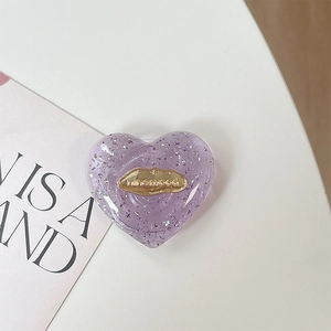 Dettaglio del supporto per telefono a cuore con paillettes viola ed emblema dorato