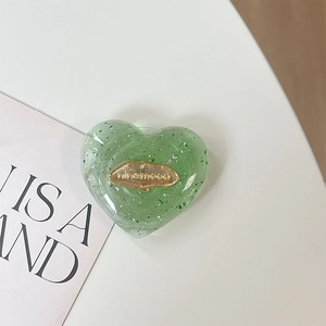 Dettaglio del supporto per telefono a cuore glitterato con labbra dorate e logo