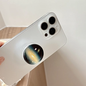Close-up of a blue galaxy nebula pop socket stand attached to a white smartphone