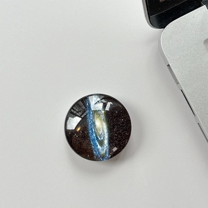 Macro shot of circular crystal glass phone grip with vibrant galaxy nebula pattern