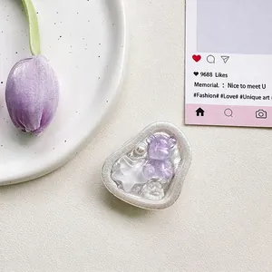 Detail of heart-shaped phone grip with a purple bear, stars, and pearls decoration