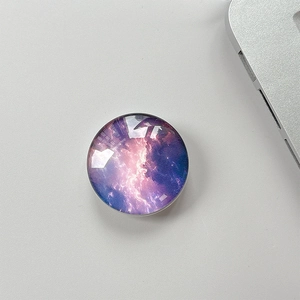Macro detail of a round crystal glass phone grip with purple starry nebula pattern