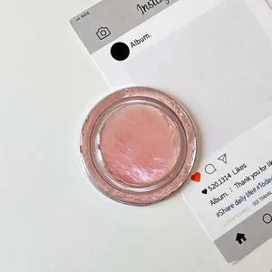 Κοντινό πλάνο κυκλικού lip balm με ροζ υφή σε διάφανη συσκευασία στο τραπέζι