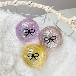 Set of three glitter sphere phone grips with black bow patterns on soft white faux fur