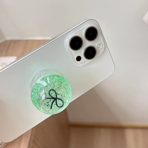 Detail of mint green sequin phone socket with bow pattern on a white smartphone