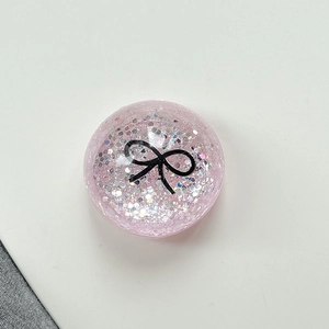 Close-up of pink glittery expandable phone grip with a minimalist black bow design