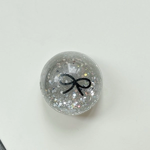 Macro shot of silver sequin-filled bubble phone grip with black bow design detail