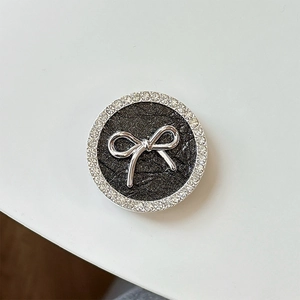 Detailed close-up of a black phone grip featuring a silver bow and sparkling rhinestones