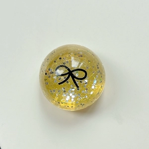 Macro detail of yellow sequin balloon phone grip with a black bow and silver glitter flakes