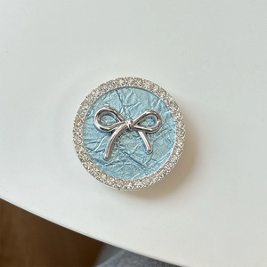 Detail of light blue pleated cell phone grip with silver bow and sparkling rhinestones