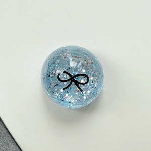 Macro detail of a light blue glitter ball phone stand with a black bow pattern