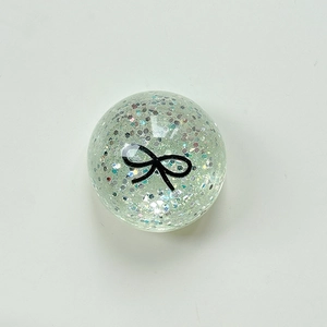 Macro shot of a transparent spherical phone grip bead with pink sequins and bow pattern