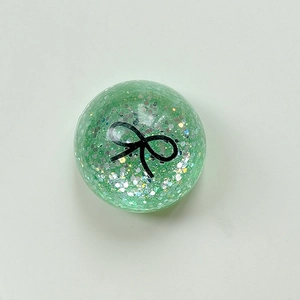 Detail of green sequin sphere phone socket with black bow pattern and glitter texture