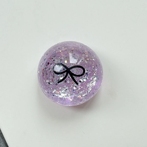 Macro detail of purple glitter phone grip with a black bow pattern on a white base