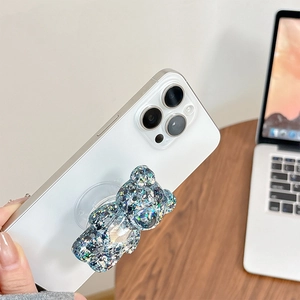 Détail d'un support de téléphone ours 3D à paillettes bleues sur un smartphone blanc