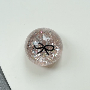 Close-up of pink sphere phone grip with glitter sequins and a black bow design