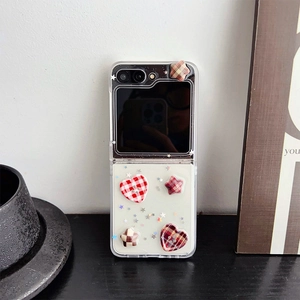 Detail of red checkered heart and star charms on transparent Z Flip case with glitter