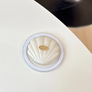 Macro shot of seashell-shaped craft with pearlescent texture and gold handmade label