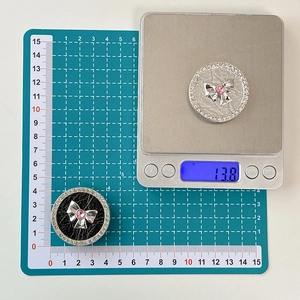 Macro detail of rhinestone bow phone grip showing 4cm diameter on a measuring mat
