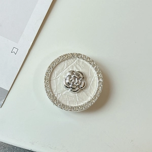 Macro detail of rhinestone-encrusted flower phone grip with pearlescent shell texture