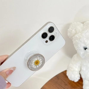Detailed macro view of a resin phone grip featuring an embedded white daisy flower