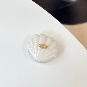Close-up of shell phone grip with glitter finish and golden Handmade metal plaque