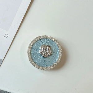 Detail of rhinestone circle phone grip with silver flower relief on blue leather texture
