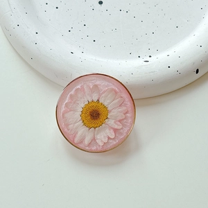 Macro shot of handmade resin phone grip featuring a real white daisy flower and pink luster