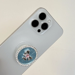 Close-up of rhinestone phone grip with silver bow and pink heart gem on leather