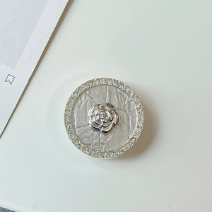 Macro detail of rhinestone-encrusted flower phone grip with silver camellia floral design