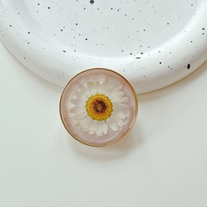 Detailed top view of a resin phone grip with a real white daisy and gold metallic edge