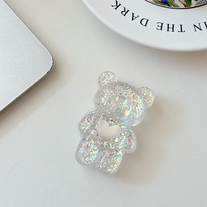 Macro shot of bear phone grip with rainbow sequins and heart cutout on white desk