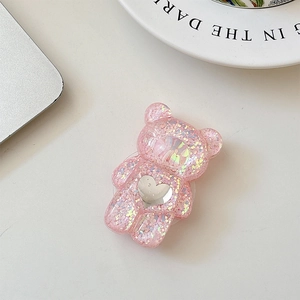 Detailed top view of pink glitter bear phone grip with mirror heart on a desk set