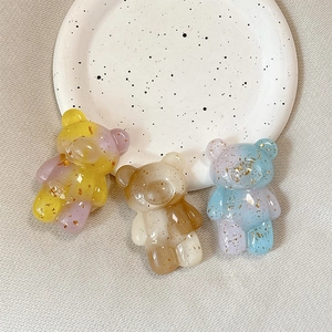 Three gradient resin bear phone stands with gold foil accents on a ceramic tray