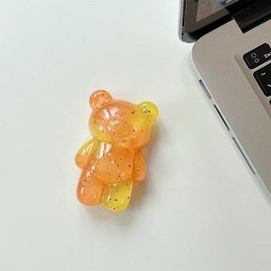 Macro detail of yellow and orange gradient bear phone holder with gold foil flakes