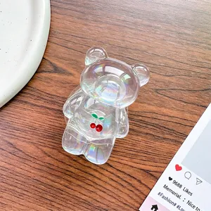Detail of laser iridescent bear phone grip with cherry ornament on dark wood background