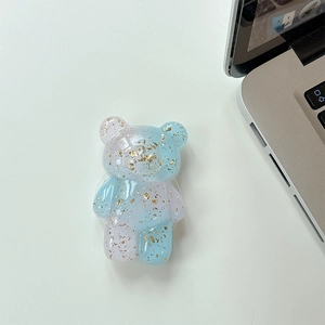 Detail shot of a transparent bear phone grip with gold foil and pink blue gradient colors