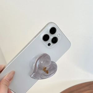 Détail du support de téléphone pailleté en forme de cœur avec lettrage Smile doré